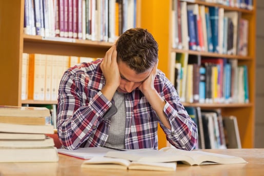 Handsome frustrated student studying his books in library