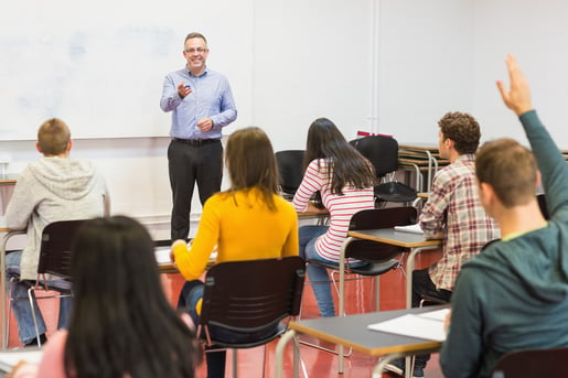 Rear view of students attentively listening to male teacher in the classroom-1