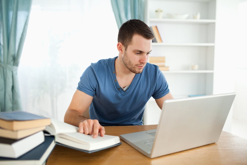 Male student using his notebook to work through his subject material