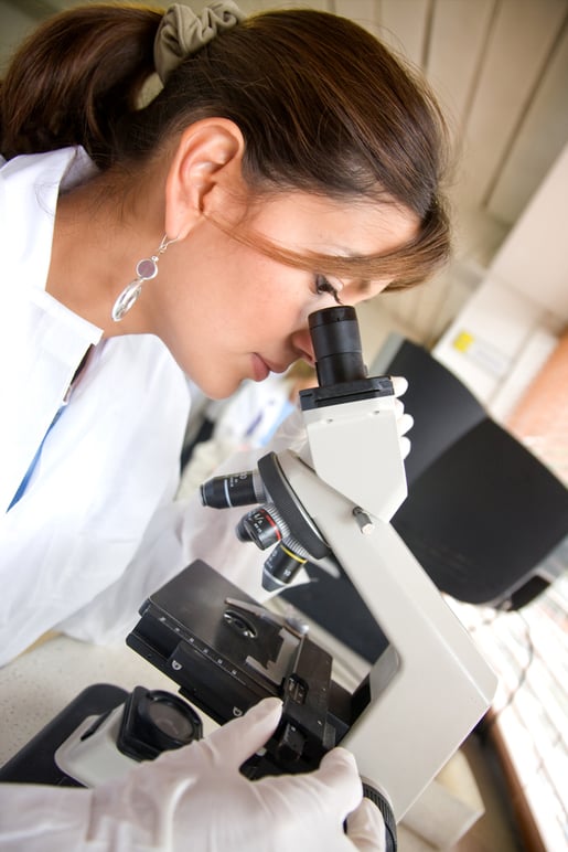 female doctor looking at samples under a microscope in a lab